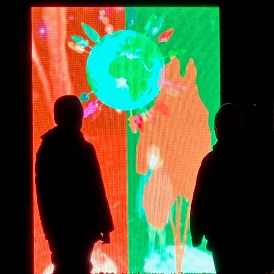 Two children pose in front of a large LED screen that turns their silhouettes into digital trees.