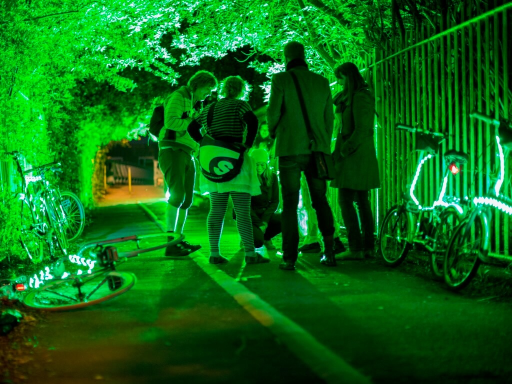 Stopping to check their map, participants' bike light up in green to illuminate a tree lined path in brilliant colour.