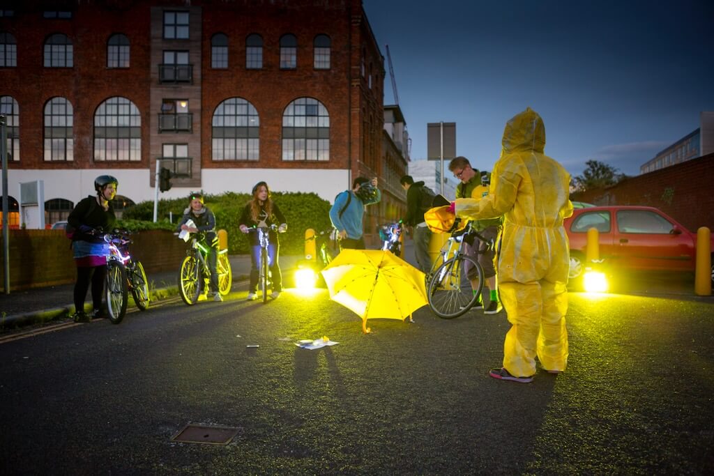 A group of adults get ready to ride their illuminated bikes.