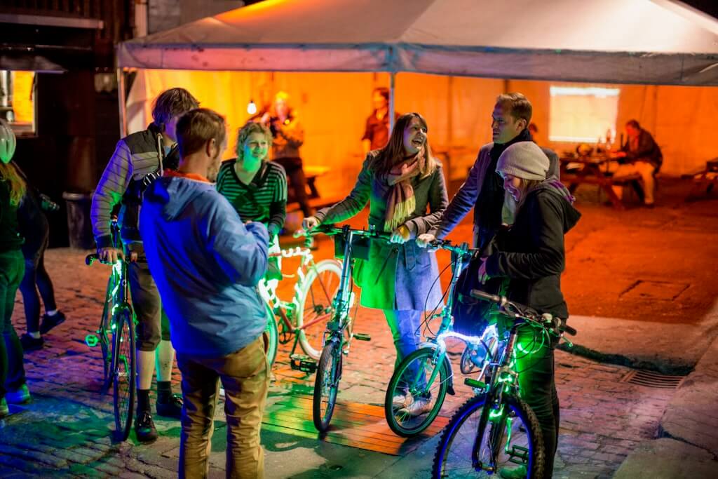 Laughter and smiles are exchanged by a group atop glowing green bikes, participants on BikeTAG.
