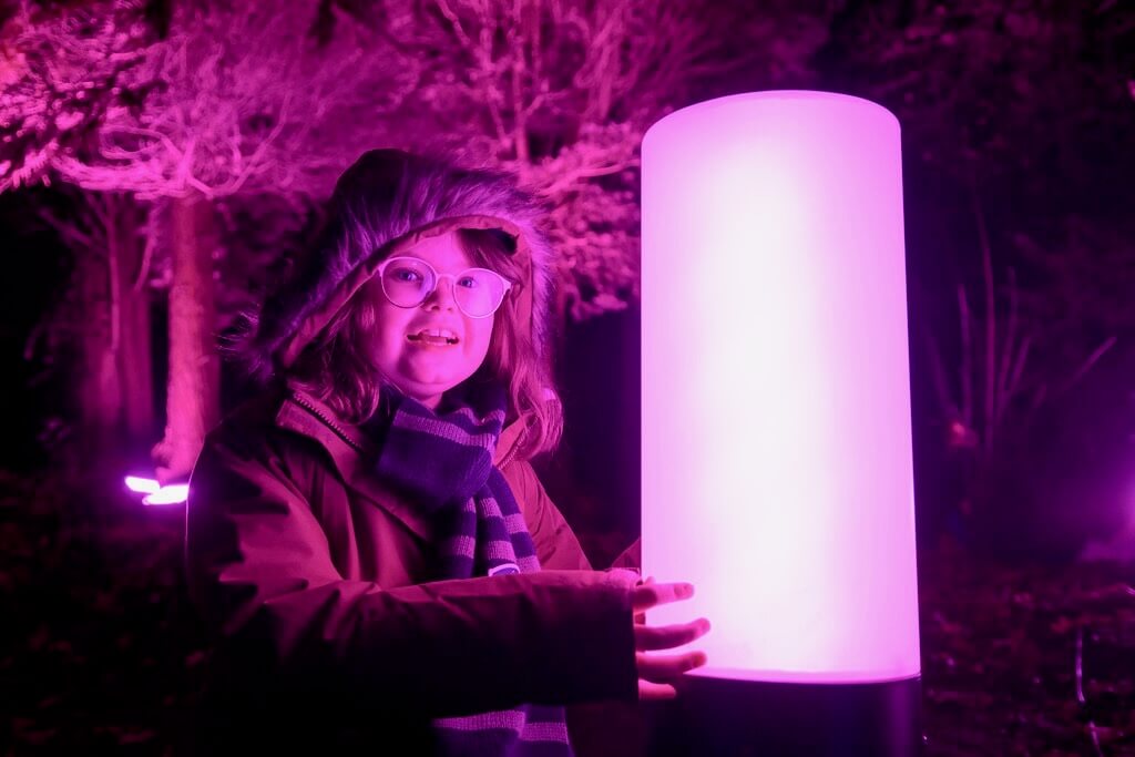 A child happily uses a podium to activate new colourful lights.