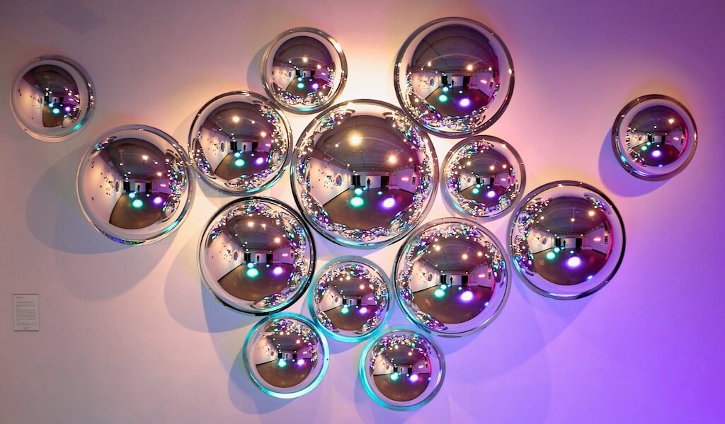 14 silver orbs curated on a wall reflect different perspective on the space they are in.