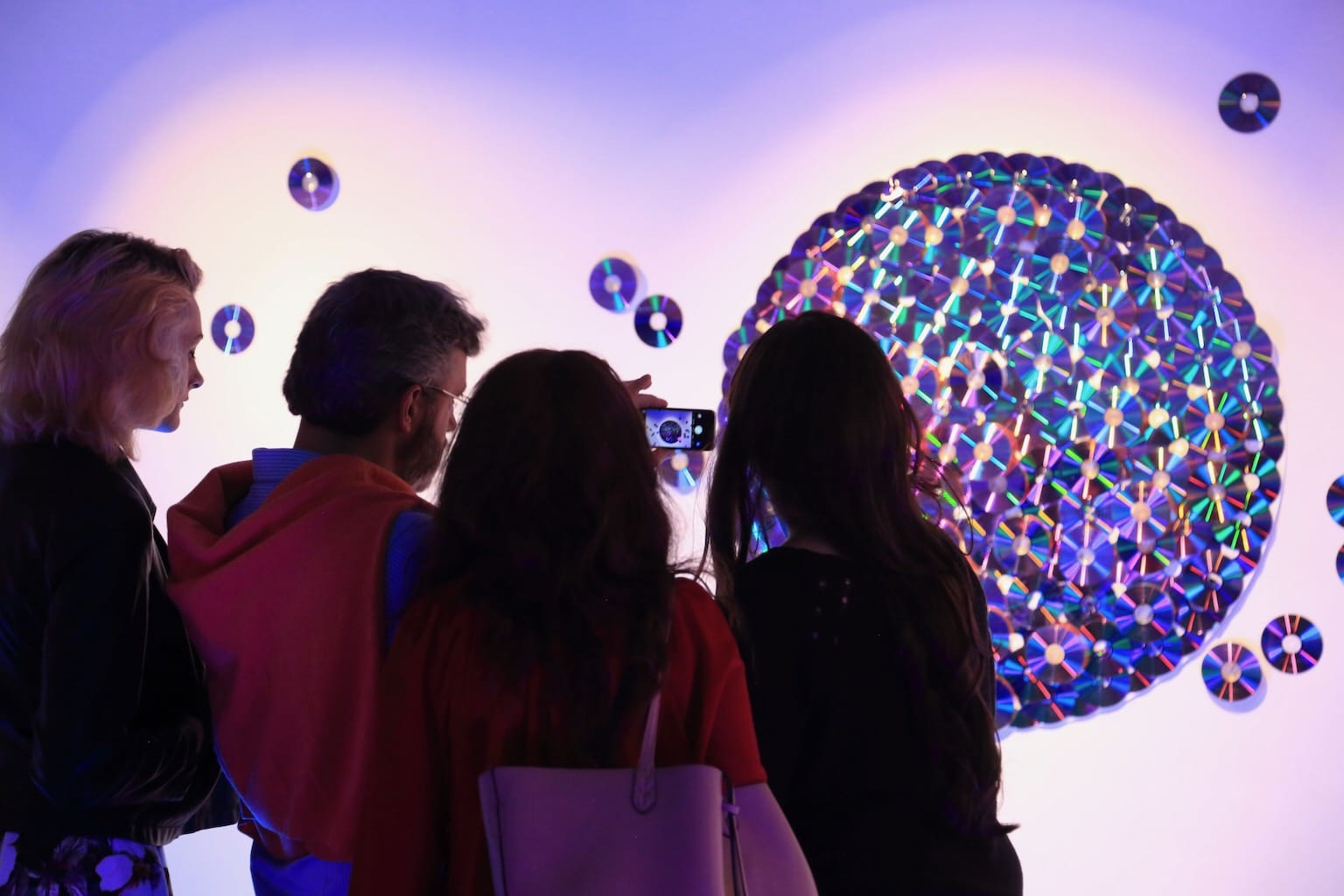 A family pauses to photograph the sculpture of reflective disks as they catch the light from different angles.