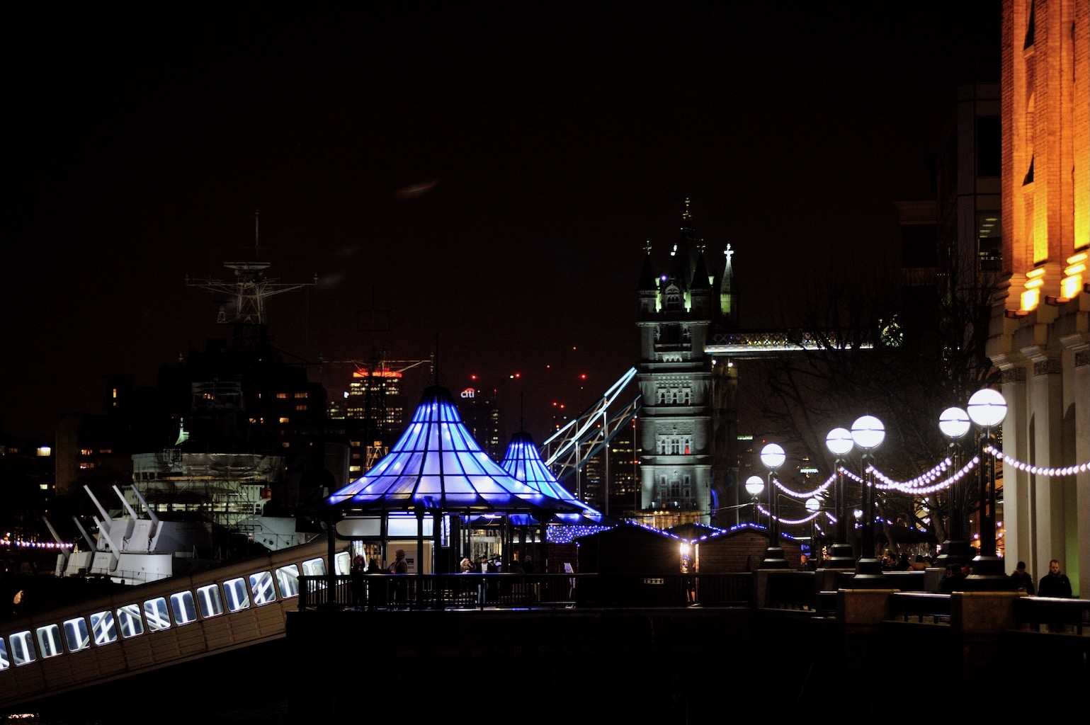 London Bridge City Pier pavilions sparkle in vibrant blue at night.