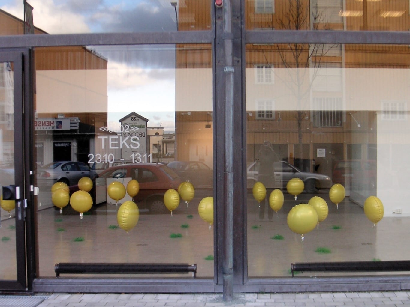 Yellow balloons beckon passers-by into an exhibition space.