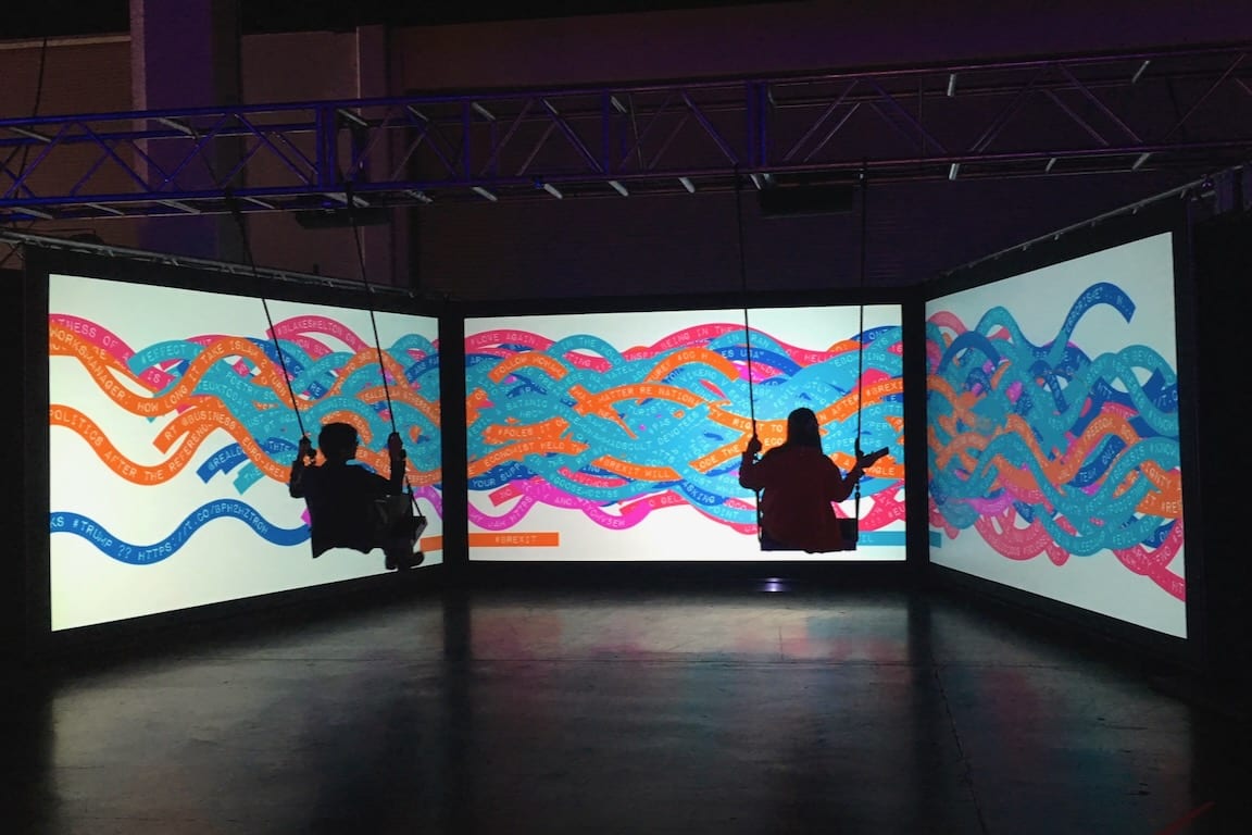 2 participants swing on Tine's interactive swing set, creating new combinations of colour and words with each movement.