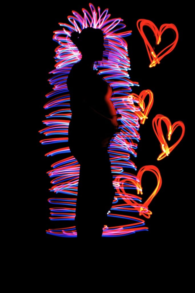 The silhouette of a woman is illuminated by strands of colourful light.