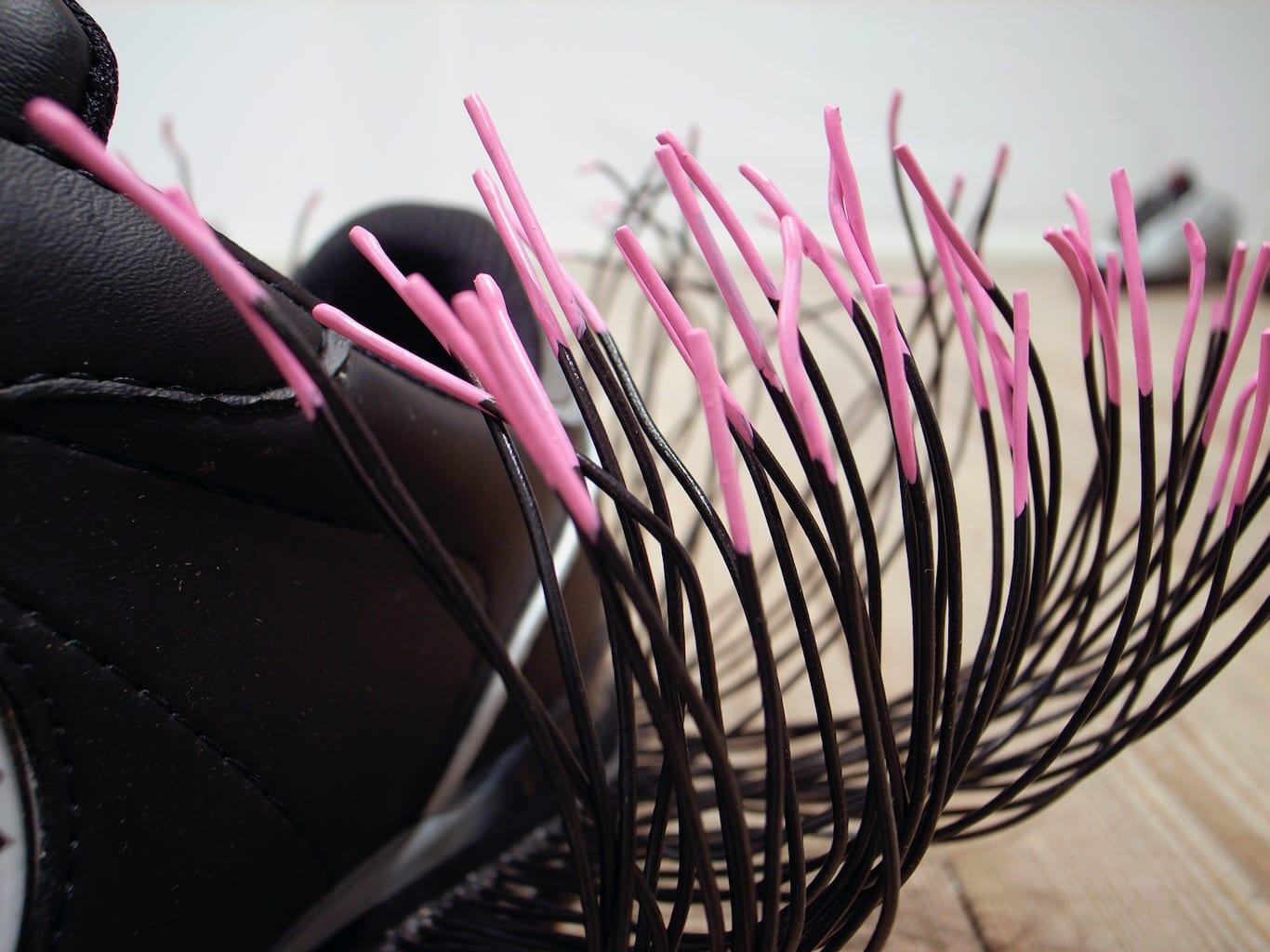 Pink and black wires emerge from a wearable shoe, the wearer dictates the noise created by the shoe based on their movement.