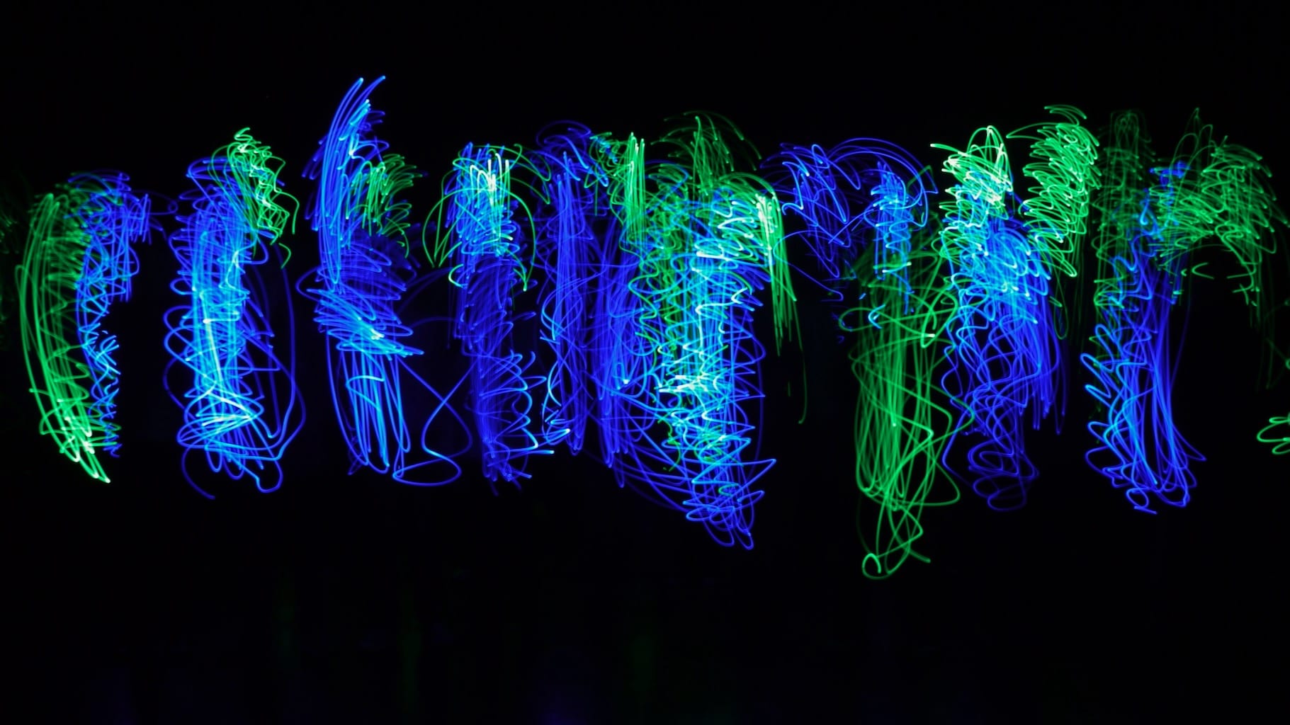 Bright blue and green swirling squiggles are created with light drawing.