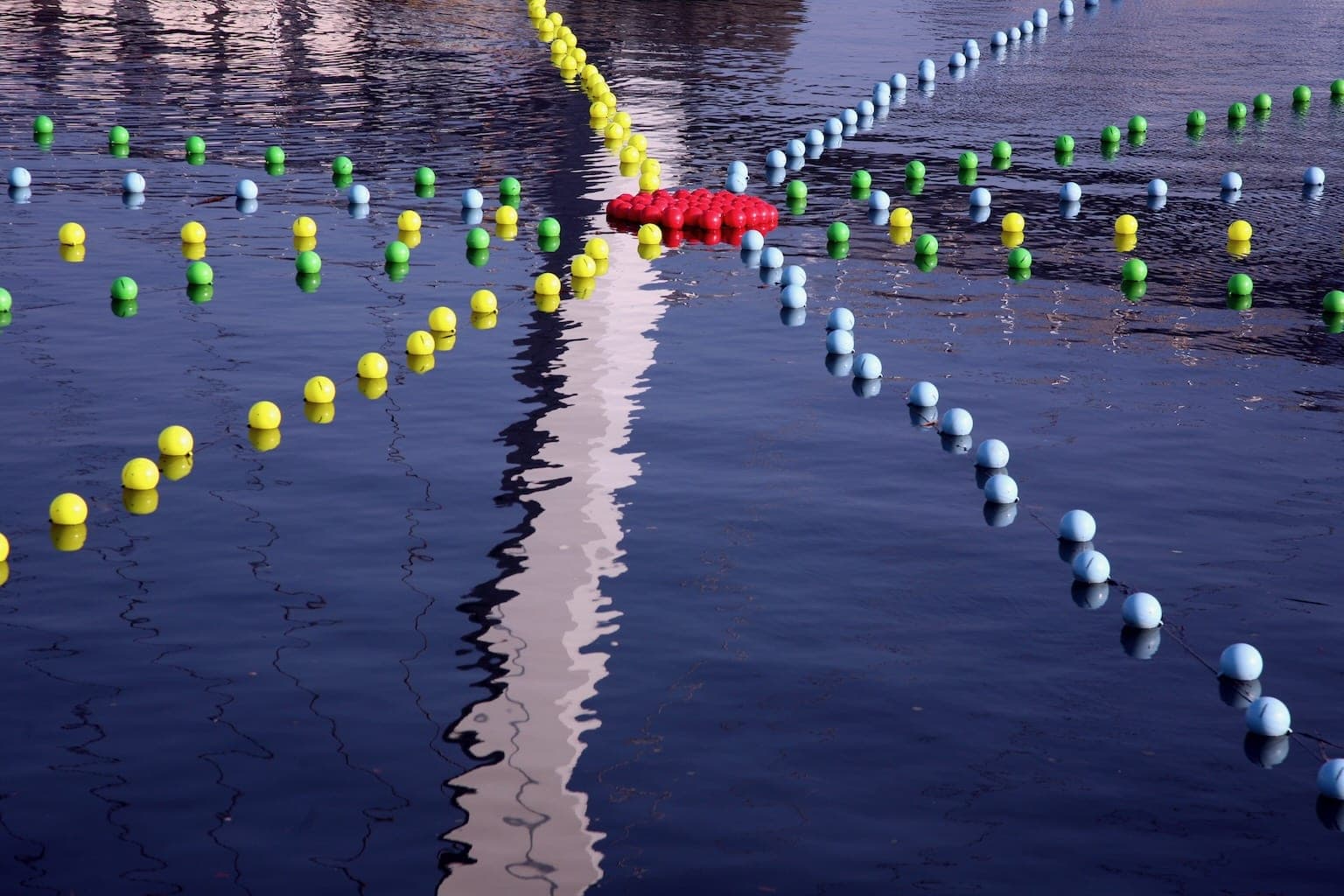The colourful buoys connect in a star pattern, reflecting on the blue river.