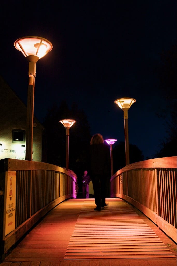 A wooden bridge is lit up in sunset shades of orange and pink.