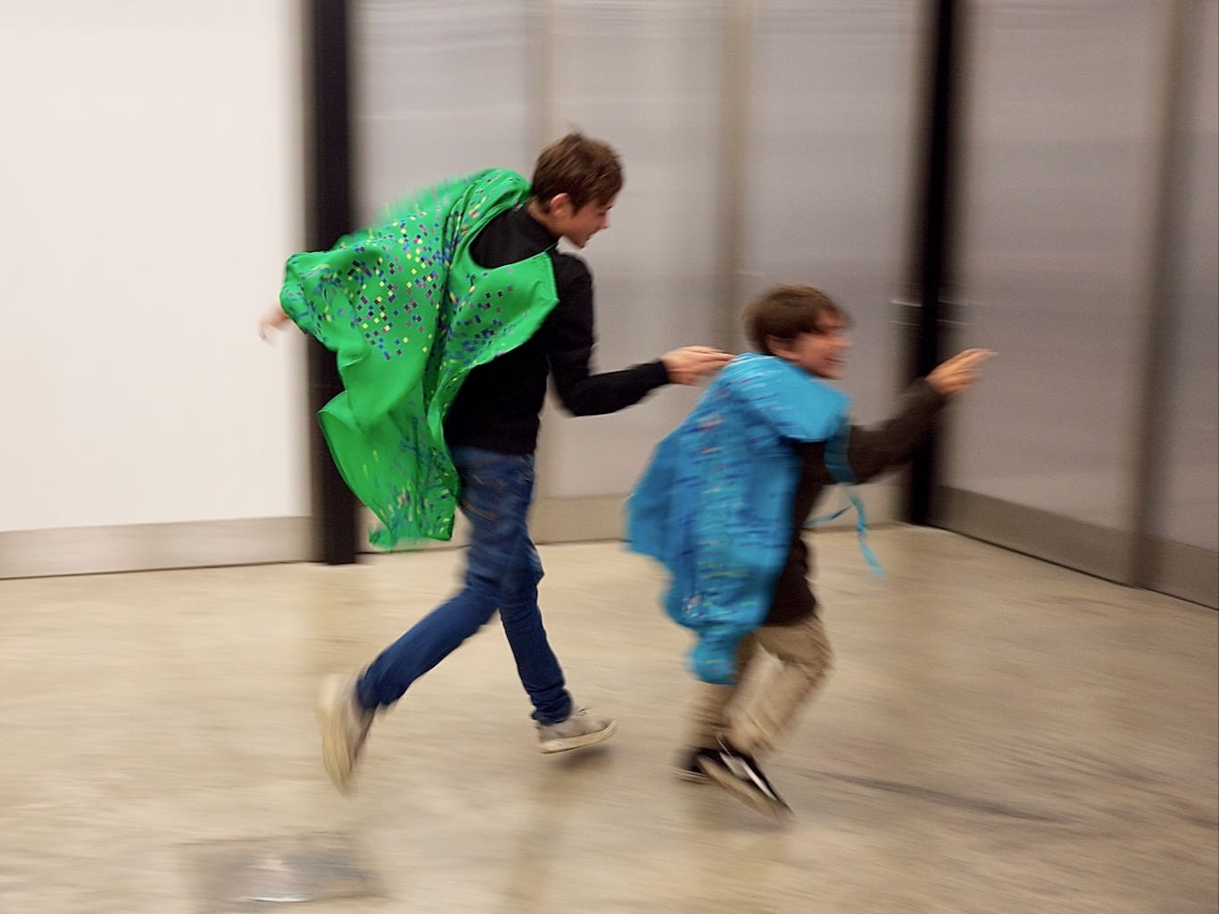 Two boys play a game of catch in capes that trigger sounds based on their wearers' movement.