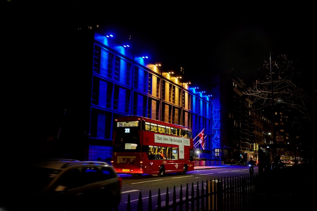 A building in London is brought to life with vibrant blue and gold spotlights.